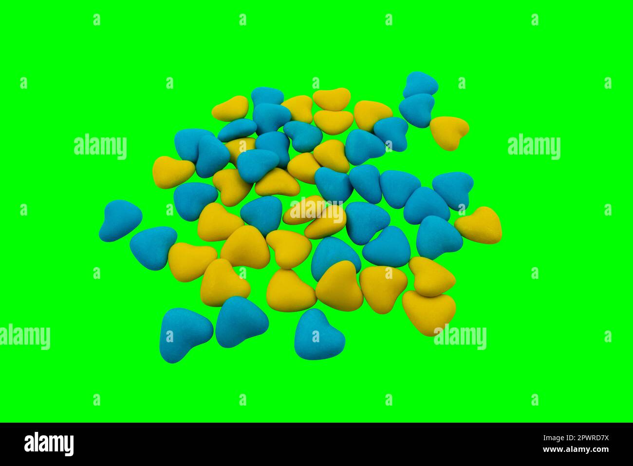Ein Haufen gelber und blauer herzförmiger Süßigkeiten (Nahaufnahme) auf grünem Hintergrund (Chroma-Schlüssel). Staatssymbole der Ukraine. Blick von oben Stockfoto