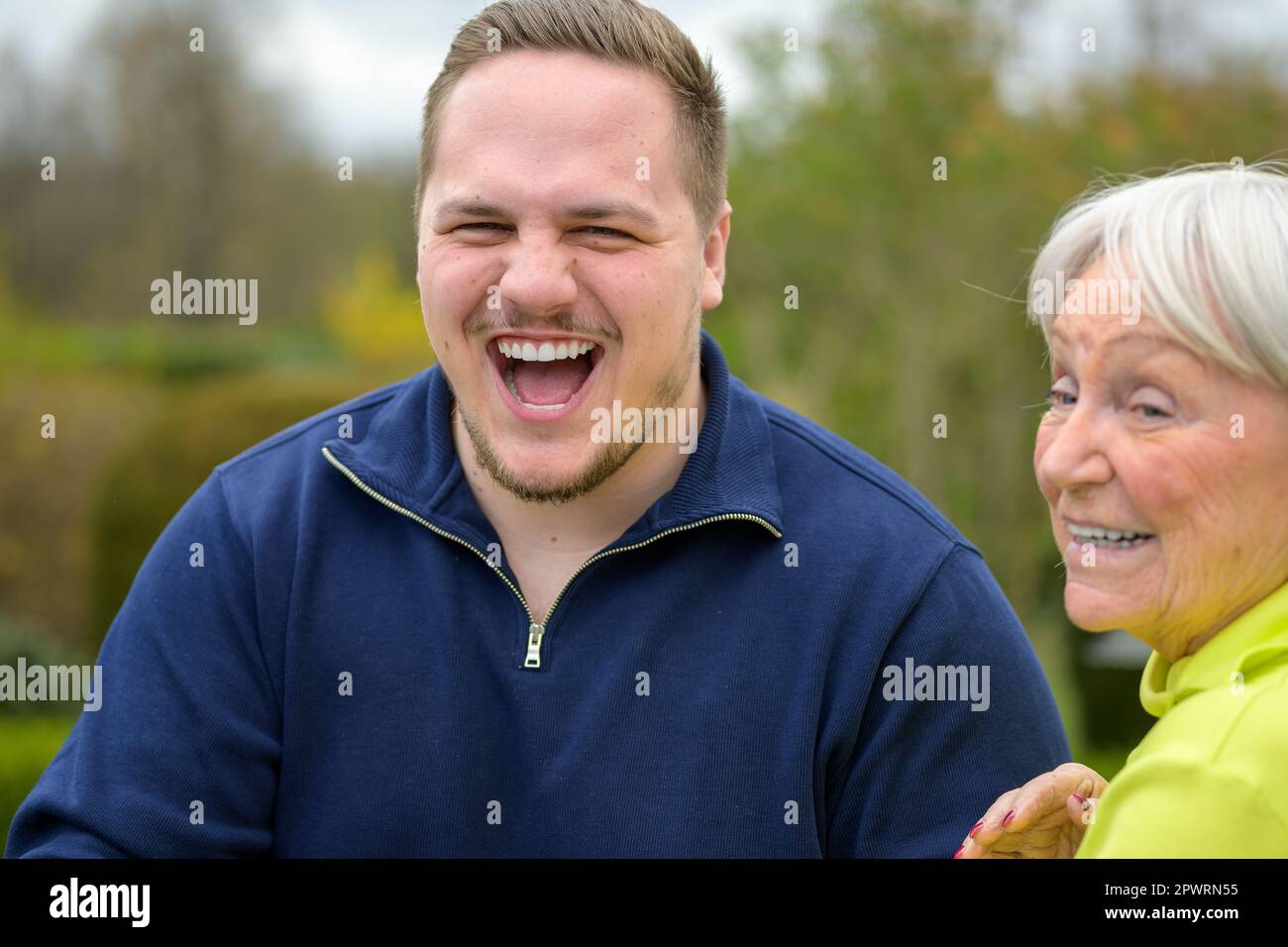 Zwei Generationen Familie, Großmutter und Enkel stehen nebeneinander und lachen Stockfoto
