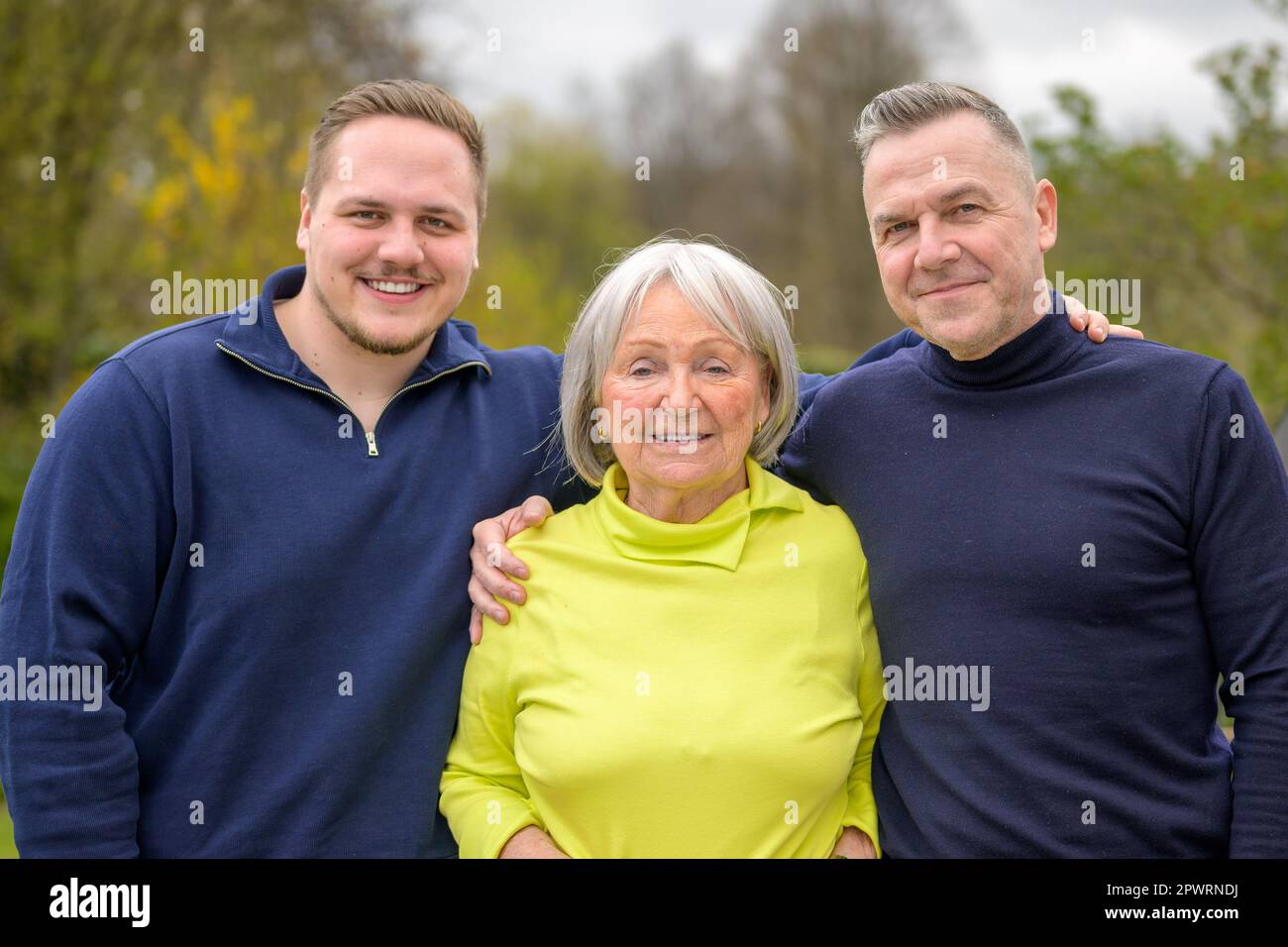 Familie der drei Generationen, Großmutter, Sohn und Enkel halten sich gegenseitig und lächeln fröhlich in die Kamera Stockfoto