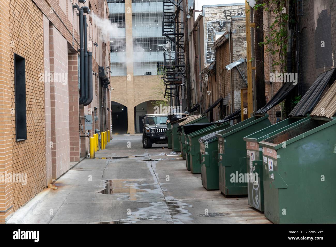 Gasse mit Mülltonnen und Hummer Auto in einer Gasse in Austin, Texas. Stockfoto