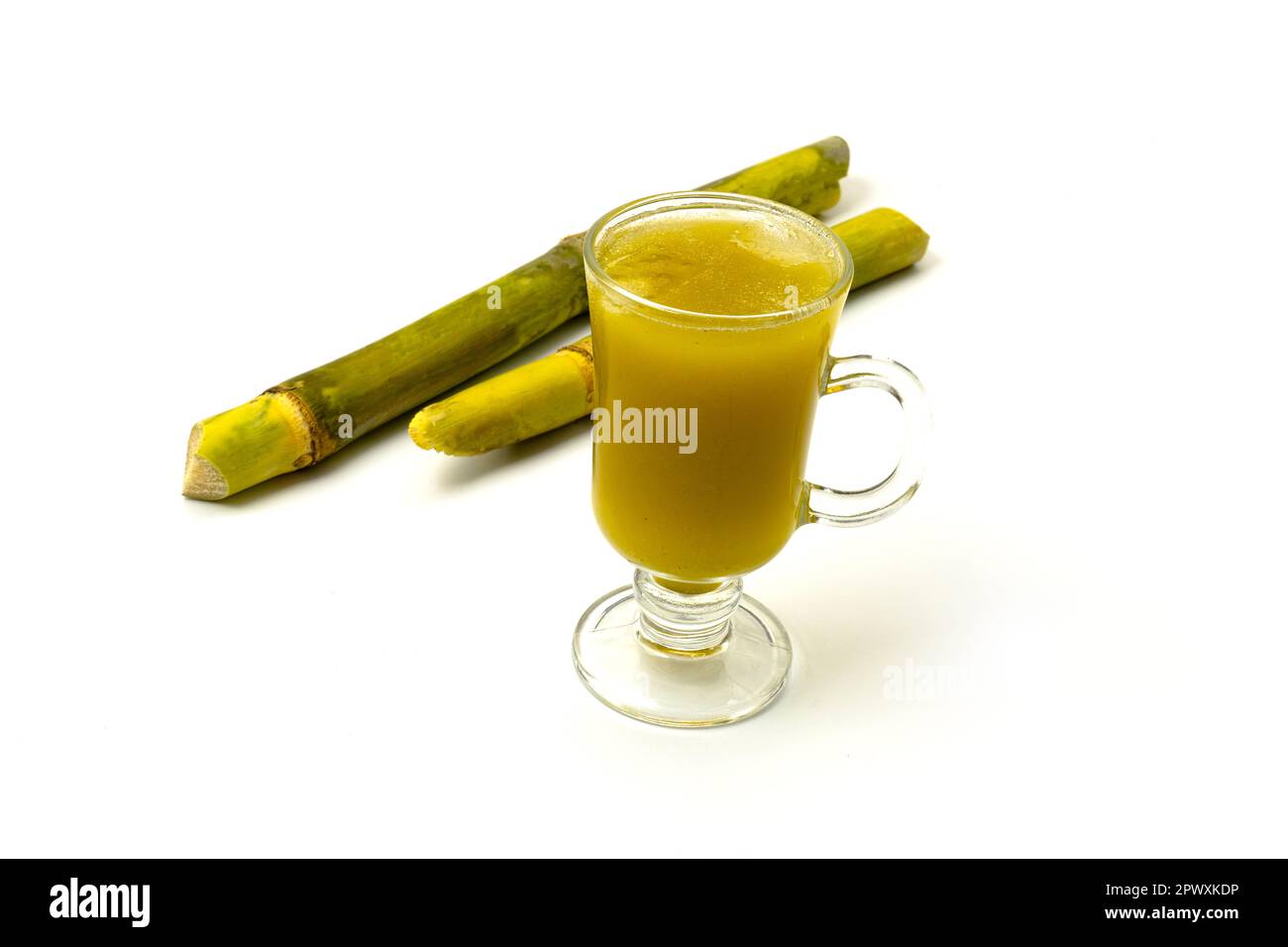 Frisch gepresster Zuckerrohrsaft mit frischem Zuckerrohr in Scheiben, isoliert auf grünem Hintergrund. Stockfoto