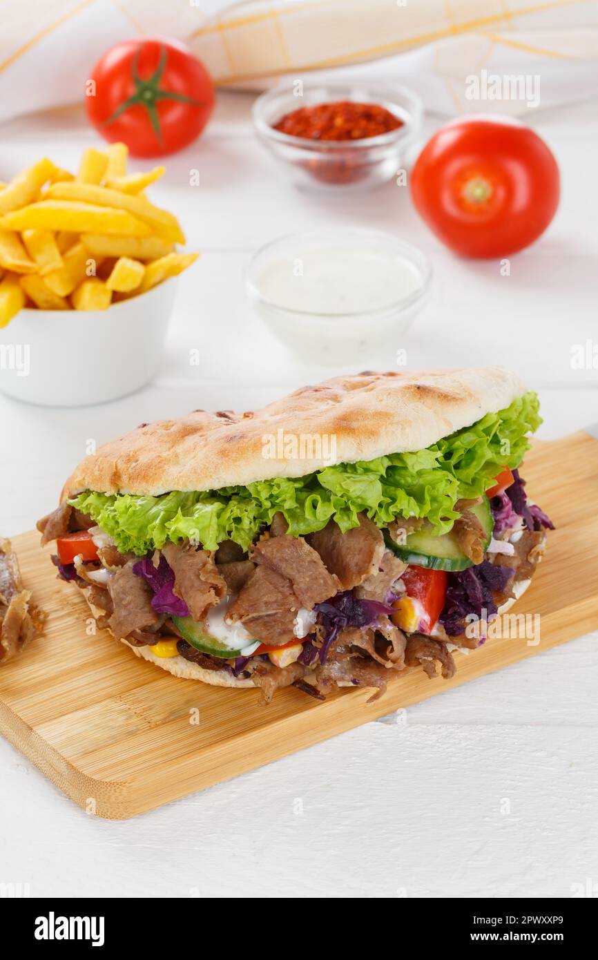 Döner Kebab Döner Kebap Fast-Food-Mahlzeit in Fladenbrot mit pommes frites auf einem Küchenbrett im Hochformat Stockfoto