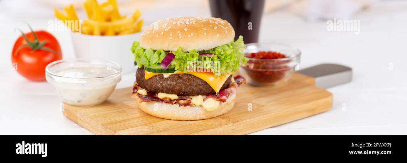 Hamburger Cheeseburger Mahlzeit Fastfood Fast Food Panorama mit Cola-Getränk und Pommes auf einem Holzbrett Menü Stockfoto