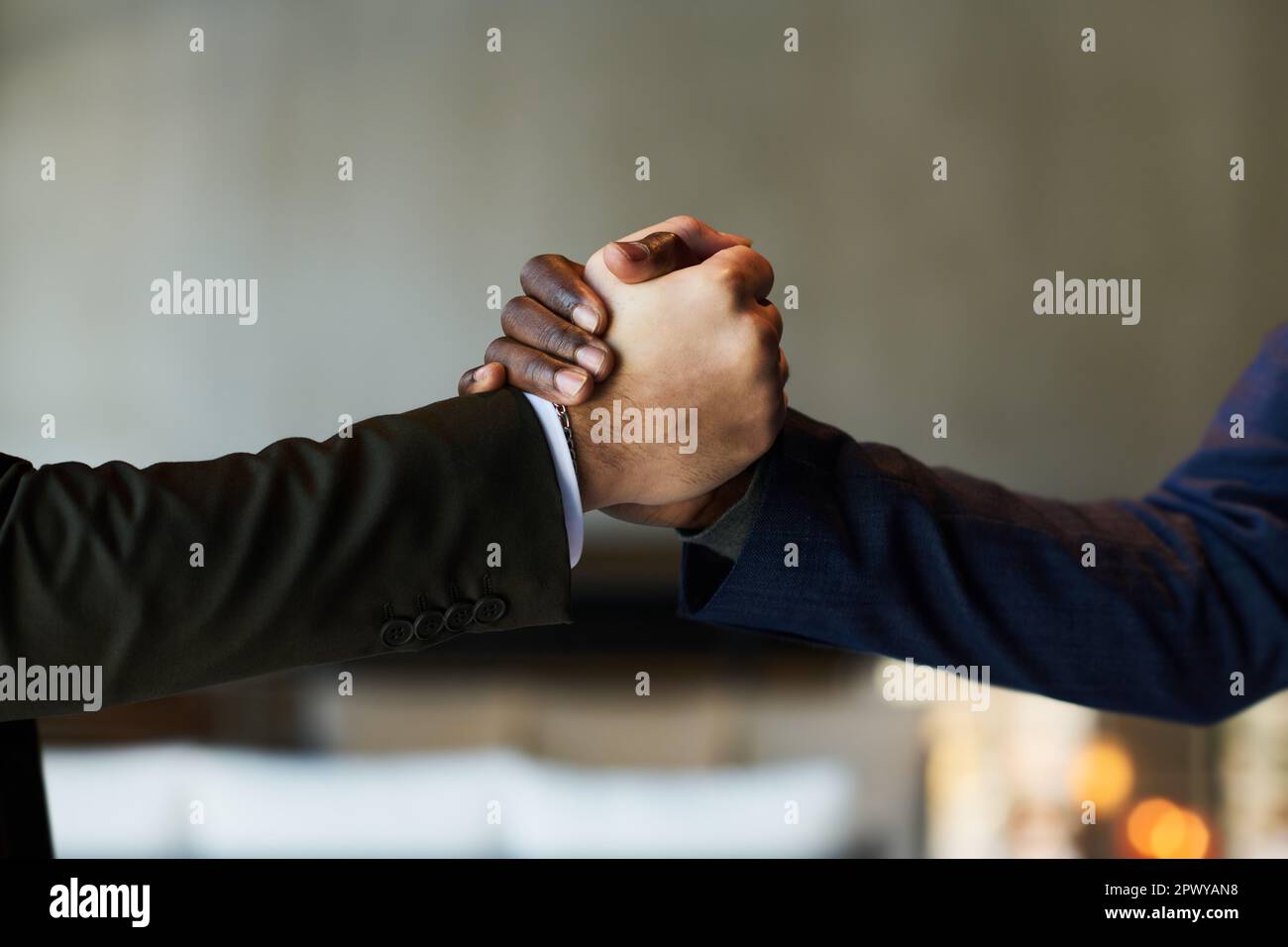 Nahaufnahme der Hände von zwei jungen männlichen Geschäftspartnern im Handschlag, die sich gegenseitig zur Unterzeichnung eines neuen Vertrags nach der Verhandlung gratulieren Stockfoto