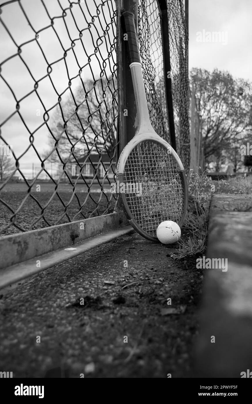 Tennisschläger und Ball gegen einen Zaun in einem Park Stockfoto