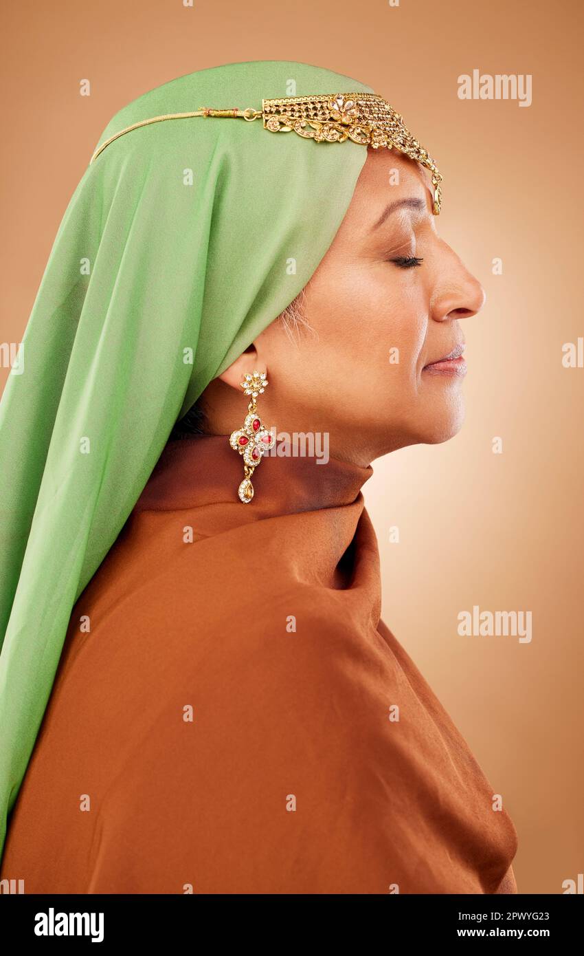 Moslem, Kulturkleidung und Seniorin mit Schmuck, Glauben und Hijab vor braunem Studiohintergrund. Islamische Mode, traditionell und bescheiden burk Stockfoto