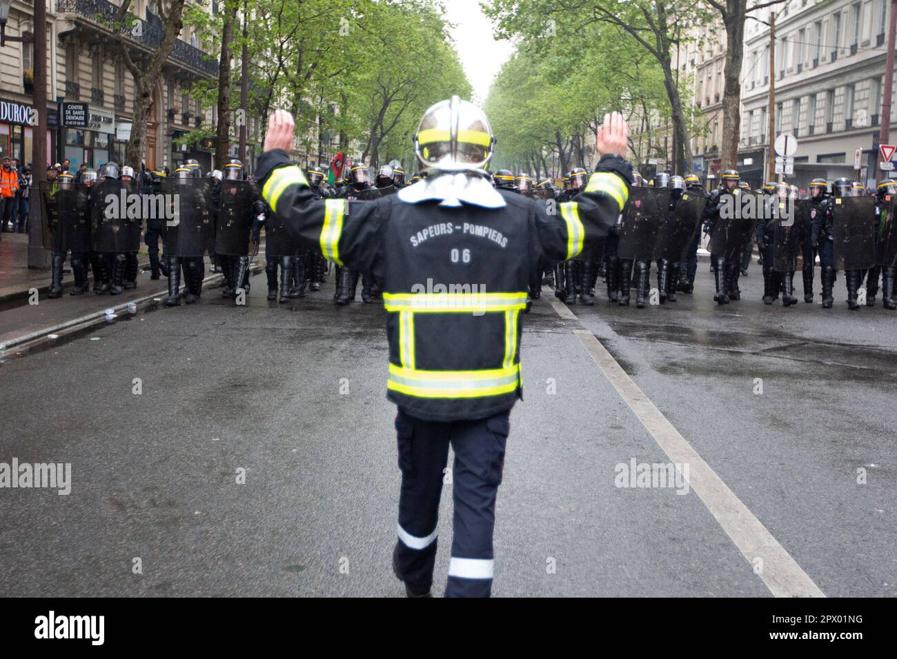 Demonstranten und französische Polizei treffen während der Bürgerkriegsaufstände am 1. Mai 2023 im Zentrum von Paris aufeinander. Viele kamen zu Wort, um ihre Abneigung gegen Präsident Macron und seine derzeitige Politik zum Ausdruck zu bringen. Hier ist ein französischer Feuerwehrmann abgebildet, der versucht, die Polizei zu beruhigen. In Frankreich auch als Sapeur-Pompier oder Pompier bezeichnet. Stockfoto