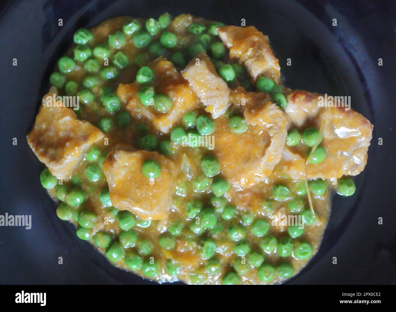 Kalbfleisch-Eintopf mit Erbsen und Zwiebeln auf dunklem Hintergrund Stockfoto