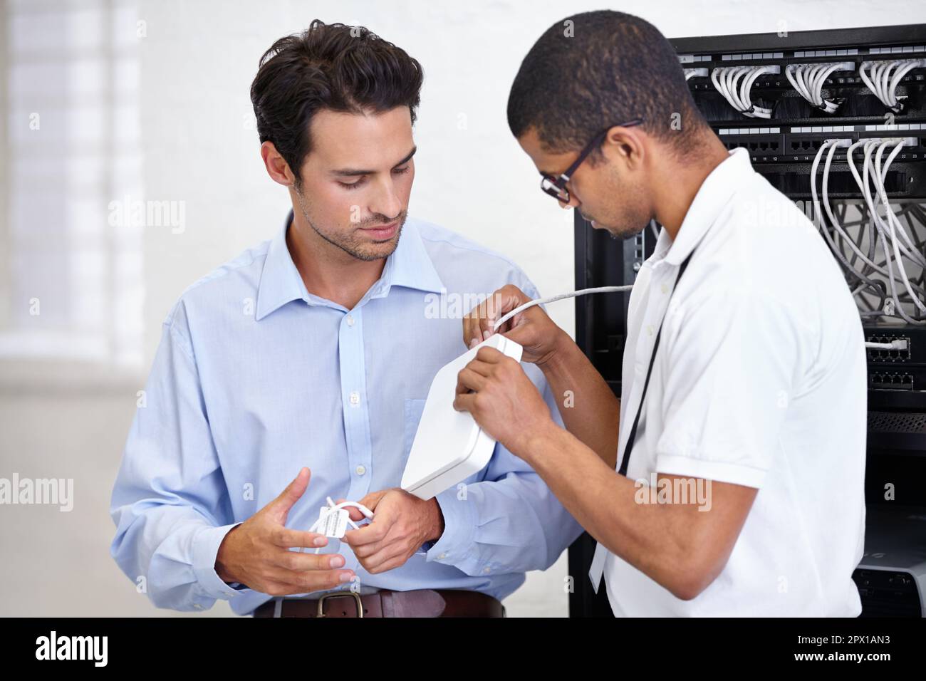 Schließen Sie das einfach an, und schon können Sie loslegen. Ein junger IT-Spezialist, der bereit ist, einen Server zu reparieren. Stockfoto