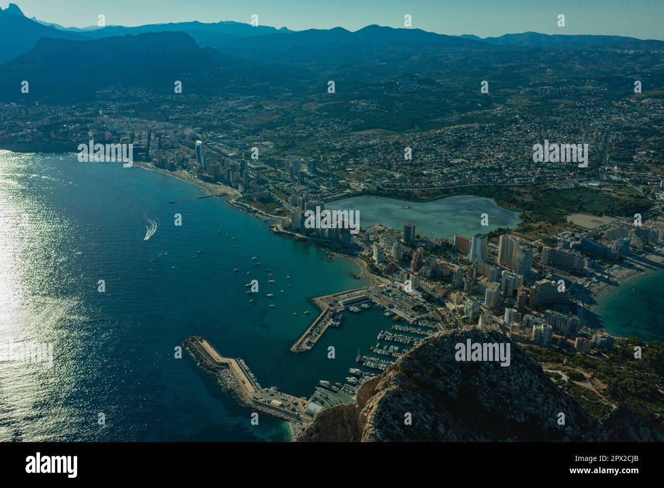 Luftaufnahme atemberaubende Penyal dIfac Naturpark von Penon de Ifach massiven Kalkstein auf dem Mittelmeer, vertäute Schiffe im Hafen von Calpe. Sunn Stockfoto