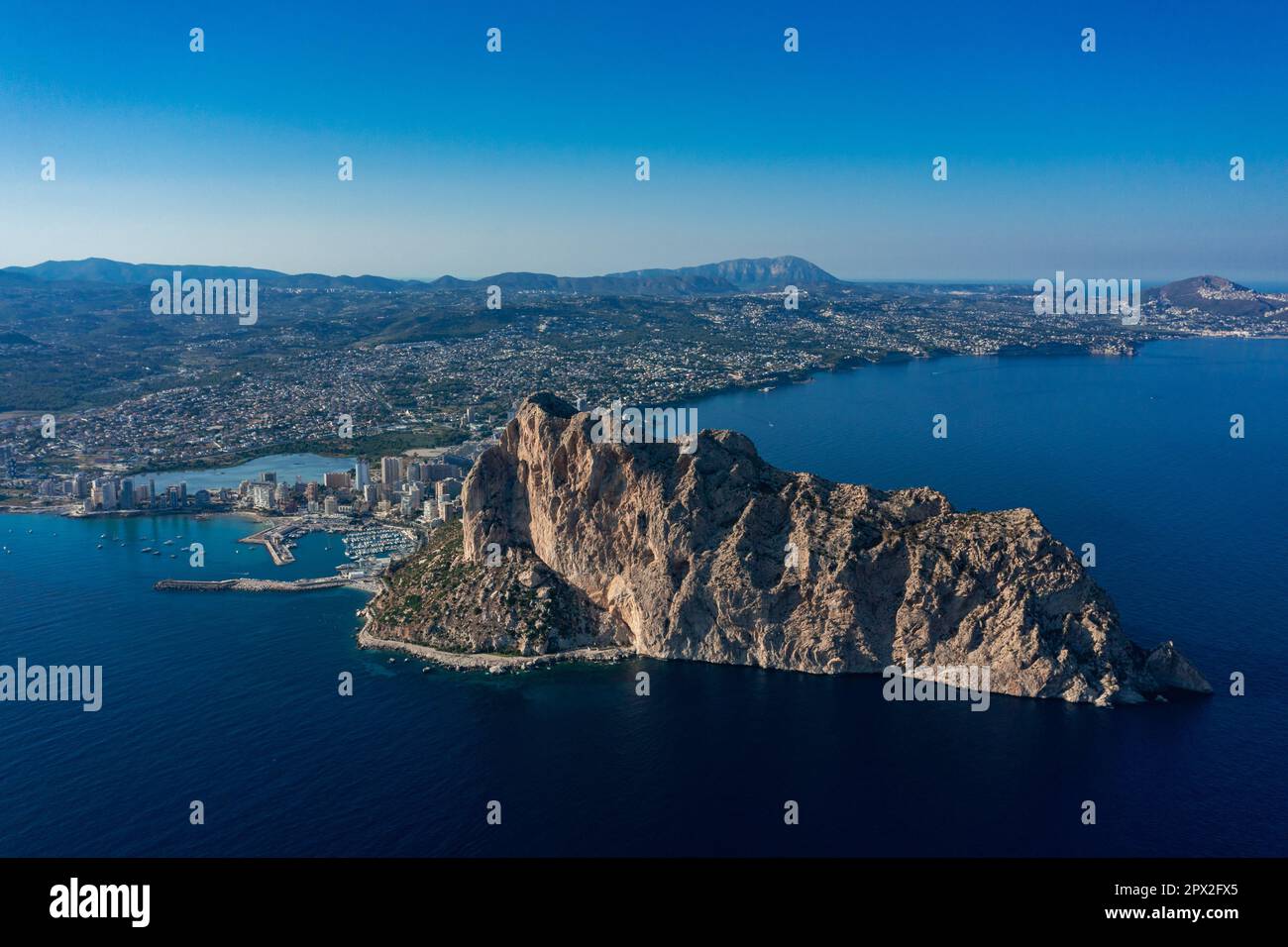 Luftaufnahme atemberaubende Penyal dIfac Naturpark von Penon de Ifach massiven Kalkstein auf dem Mittelmeer, vertäute Schiffe im Hafen von Calpe. Sunn Stockfoto