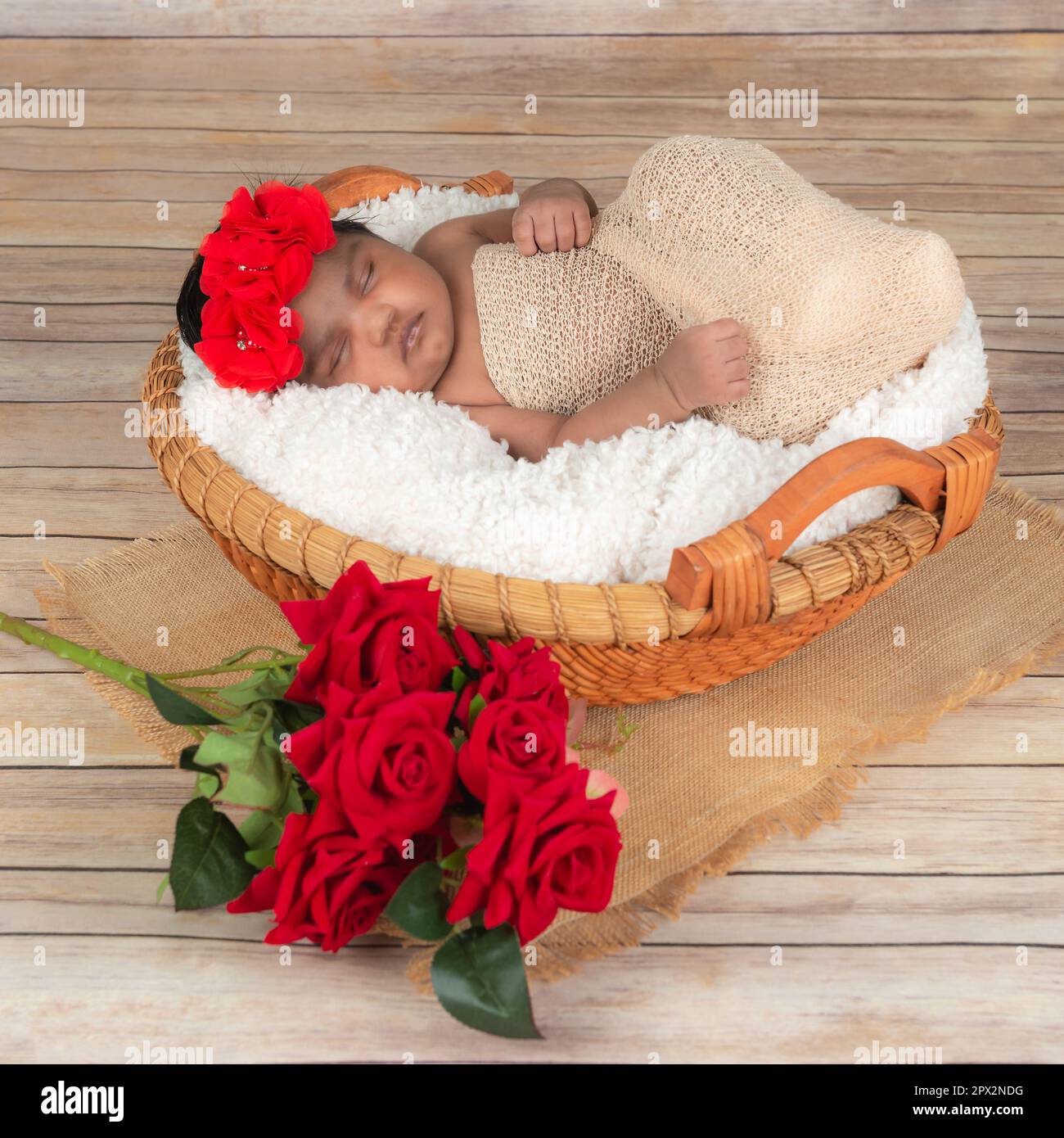 Babymädchen Schlafstudio Fotoshooting Rosen und Korb auf Holzboden Stockfoto