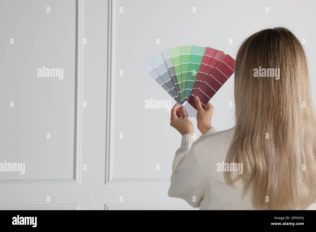 Eine Frau mit Farbsplittern, die die Farbe für die Wand in Innenräumen wählt. Innendesign Stockfoto