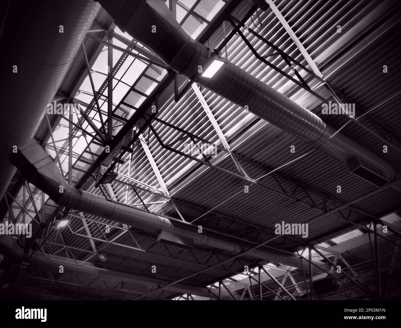Das Dach eines Hangars, einer Produktionshalle oder einer Sporthalle. Metallkonstruktionen, Balken, Stützelemente. Lüftungsanlagen in großen Hallen und Räumen. Stockfoto