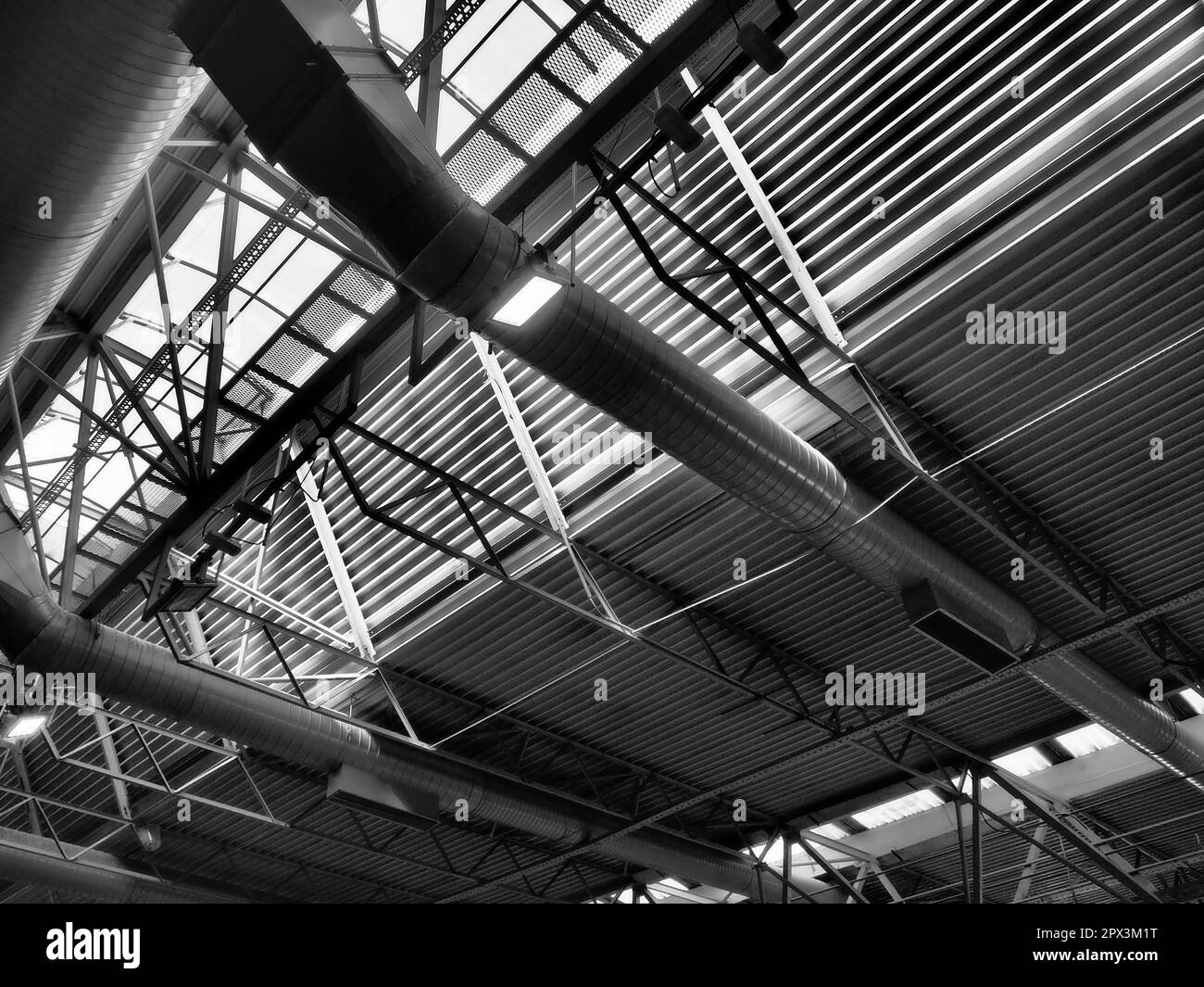 Das Dach eines Hangars, einer Produktionshalle oder einer Sporthalle. Metallkonstruktionen, Balken, Stützelemente. Lüftungsanlagen in großen Hallen und Räumen. Stockfoto