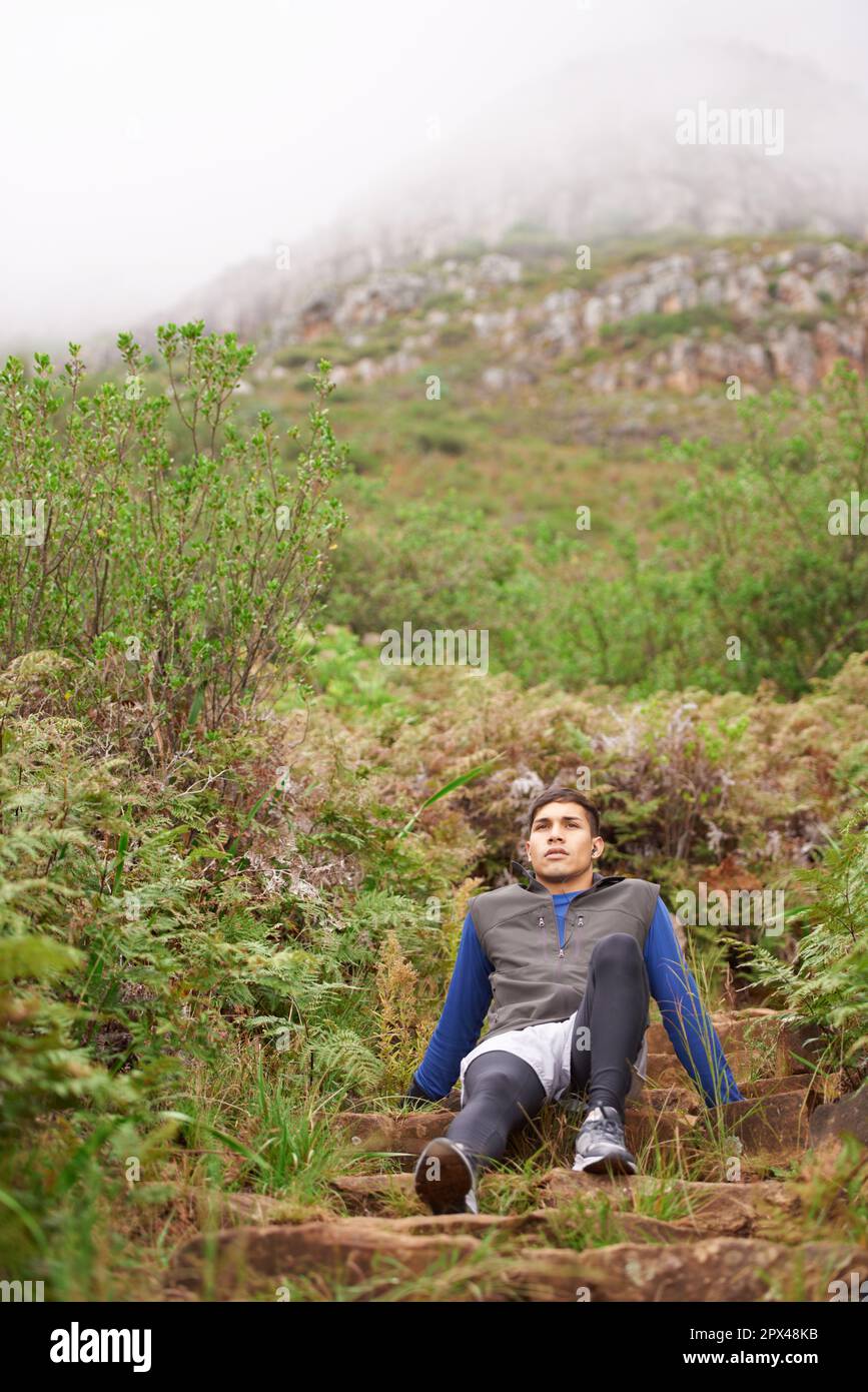 Was für ein Workout. Ein junger Mann, der draußen in den Bergen sitzt. Stockfoto