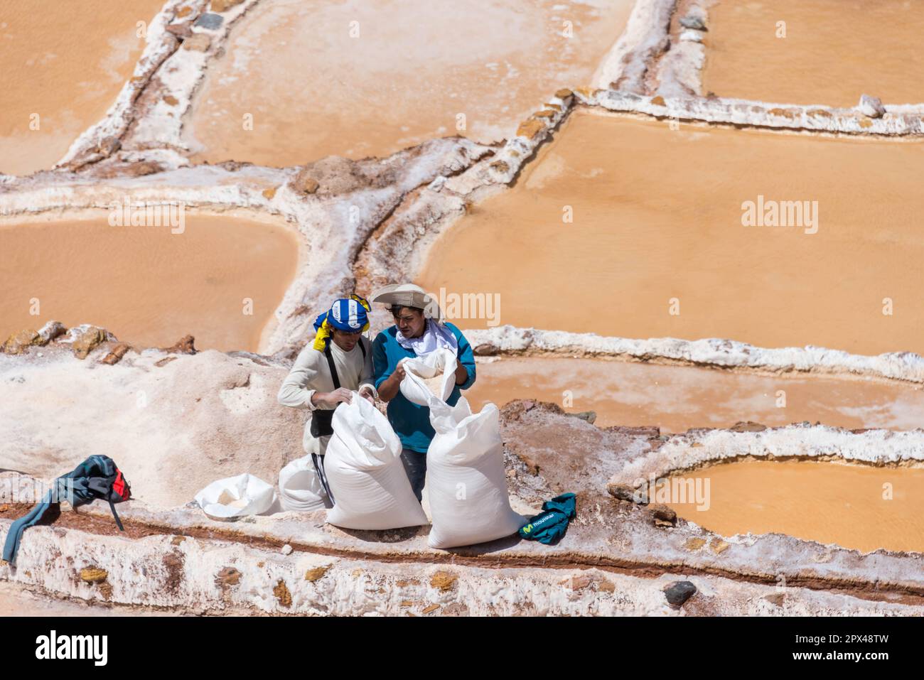 Maras, Peru - 19. 2018. Oktober: Zwei Männer sammeln gefiltertes Salz aus der Salinera, um es später zu verkaufen Stockfoto