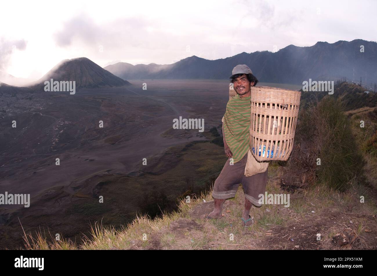 Einheimischer Dorfbewohner mit Graskorb mit Mount Batok im Hintergrund, Bromo Tengger Semeru National Park, Ost-Java, Indonesien Stockfoto