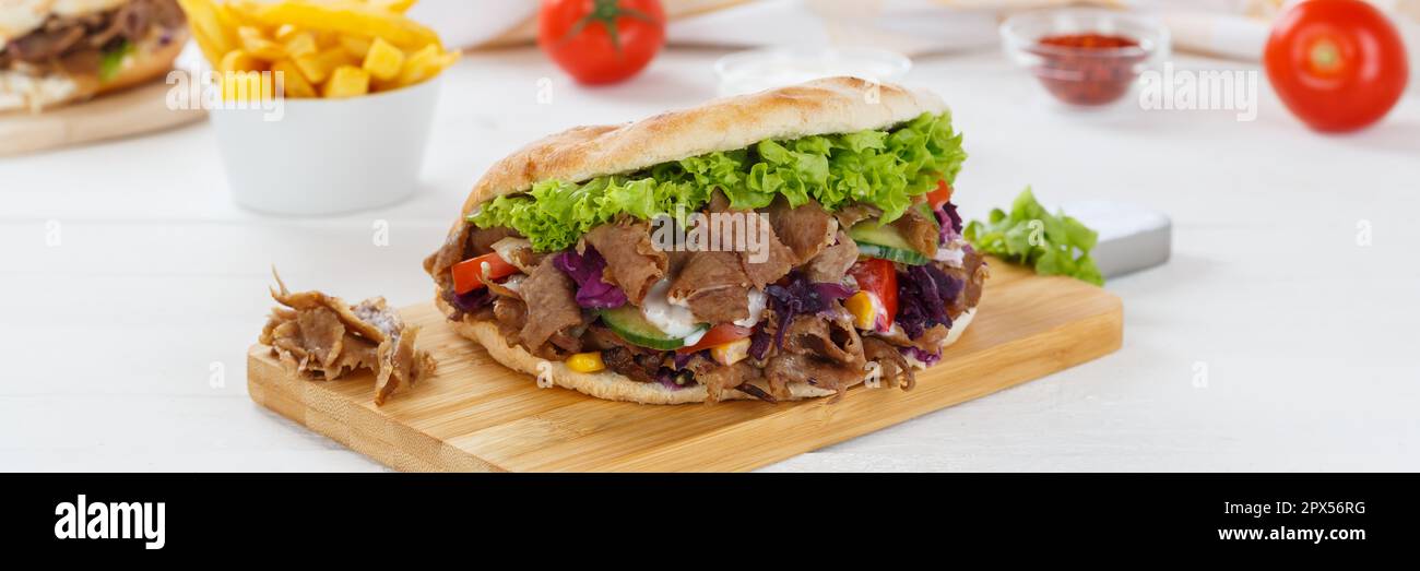 Döner Kebab Döner Kebap Fast-Food-Mahlzeit in Fladenbrot mit pommes frites auf einem Küchenbrett-Panorama Stockfoto