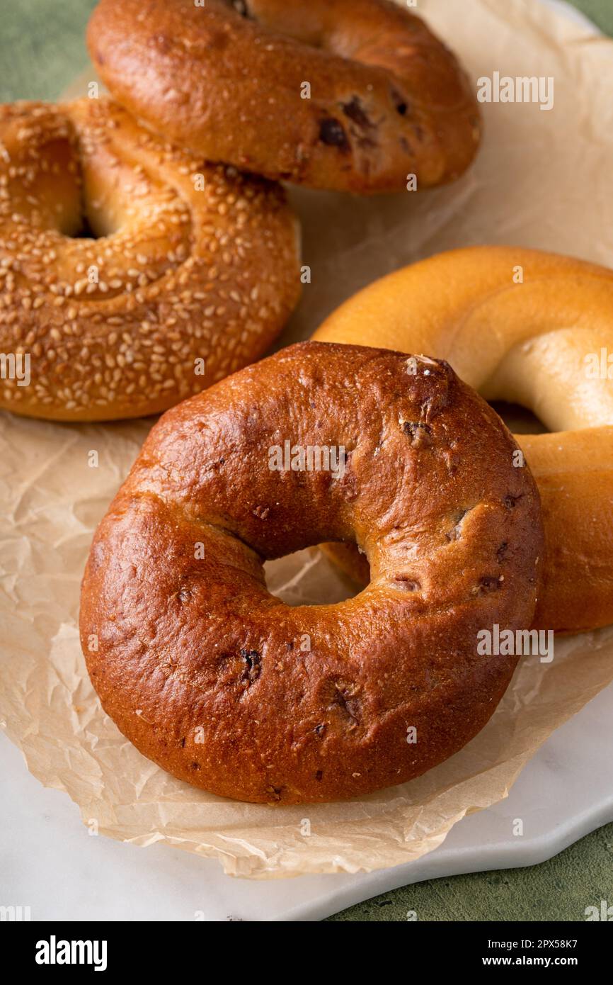 Hausgemachte, frisch gebackene Bagels auf Pergamentpapier, verzehrfertig, Zimtrosinen, Sesam und Bagel Stockfoto