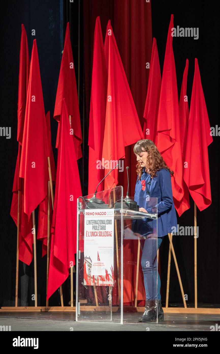 Eine Aktivistin von Lotta Comunista auf der Bühne während ihrer Rede mit den roten Fahnen im Hintergrund. Wanderarbeiter aus den römischen Vororten waren Ehrengäste bei der traditionellen Feier zum Mai, die Lotta Comunista, die exparlamentarische, internationalistische Bewegung, jedes Jahr im Teatro Brancaccio in Rom organisiert. Die wichtigsten Leitmotive der diesjährigen Konferenz waren ein entschiedenes Nein zum Frieden mit Waffen, die entschiedene Ablehnung jeglicher Form von Fremdenfeindlichkeit und die Notwendigkeit, die Proletarier der ganzen Welt zu vereinen. (Foto: Marcello Valeri/SOPA Images/Sipa USA) Stockfoto