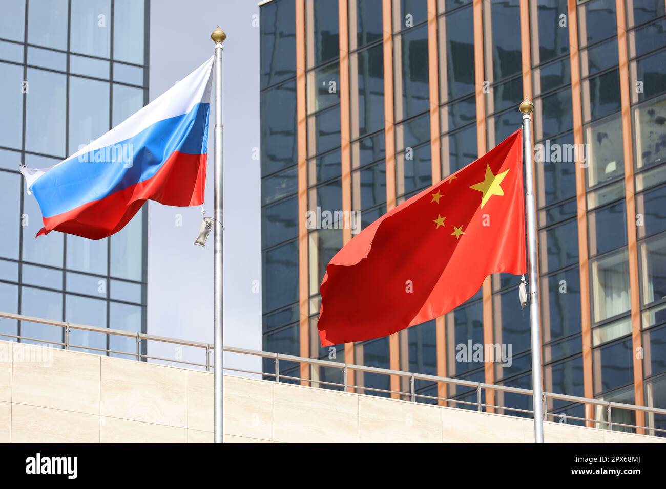 Flaggen Chinas und Russlands auf Wolkenkratzerhintergrund. Konzept der politischen und wirtschaftlichen Zusammenarbeit, des Handels und der Unterstützung durch China und Russland Stockfoto