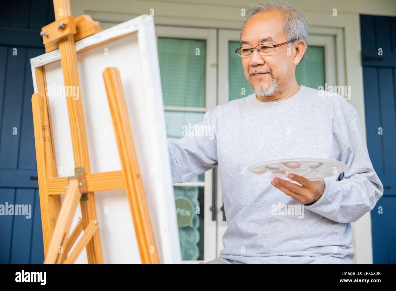 Lifestyle Ältere Menschen lächeln an seiner Staffelei draußen zu Hause, asiatischer älterer Mann malt Bild mit Pinsel- und Ölfarbe auf Leinwand, Happy retir Stockfoto