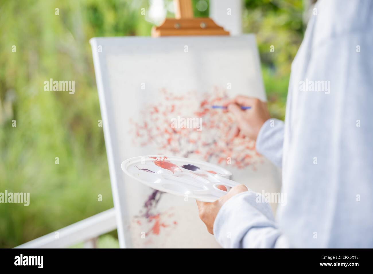 Lifestyle-Künstler. Ein alter Mann malte Bilder mit Pinsel- und Wasserfarben auf Leinwand, porträtiert ältere weiße Haarfarbe an seiner Staffelei Stockfoto