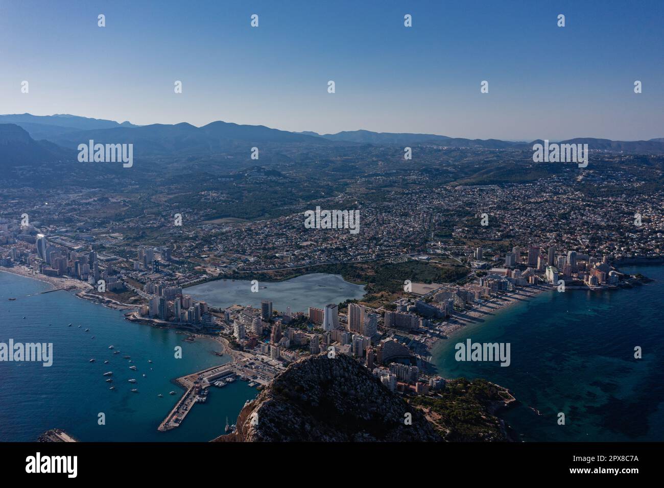 Luftaufnahme atemberaubende Penyal dIfac Naturpark von Penon de Ifach massiven Kalkstein auf dem Mittelmeer, vertäute Schiffe im Hafen von Calpe. Sunn Stockfoto
