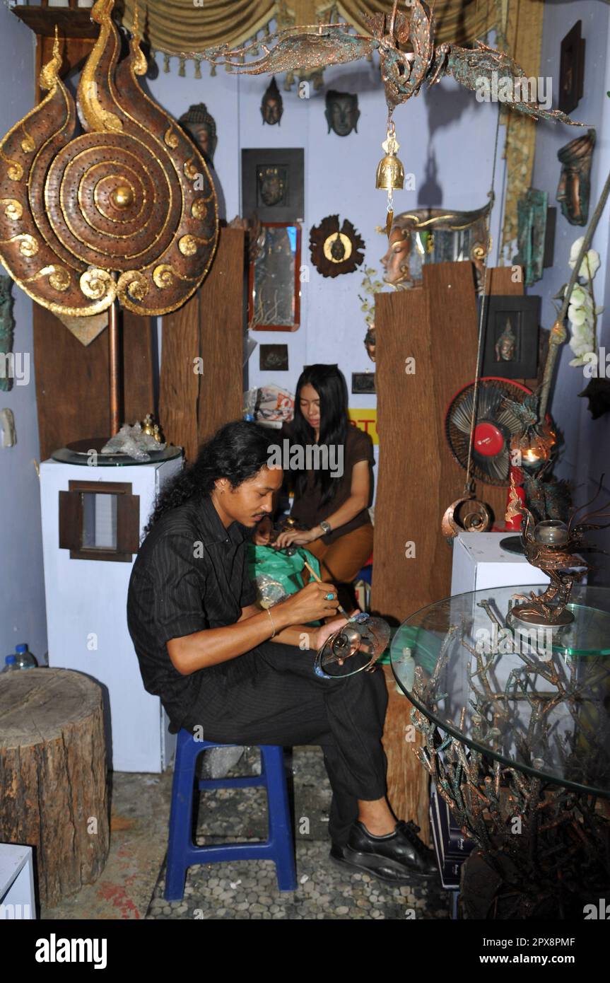 Ein Kellner, der in seinem Geschäft auf dem farbenfrohen und lebendigen Chatuchak Wochenendmarkt in Bangkok, Thailand, arbeitet. Stockfoto