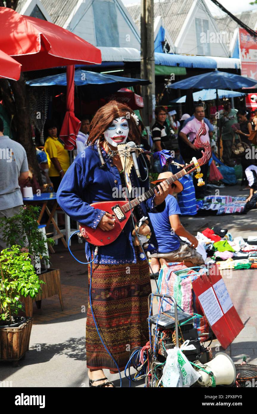 Ein Straßenmusiker spielt auf dem farbenfrohen und lebendigen Chatuchak Wochenendmarkt in Bangkok, Thailand. Stockfoto
