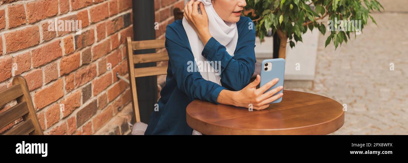 Glückliche muslimische Frau mit Videoanruf auf dem Smartphone in der Stadt. Stockfoto