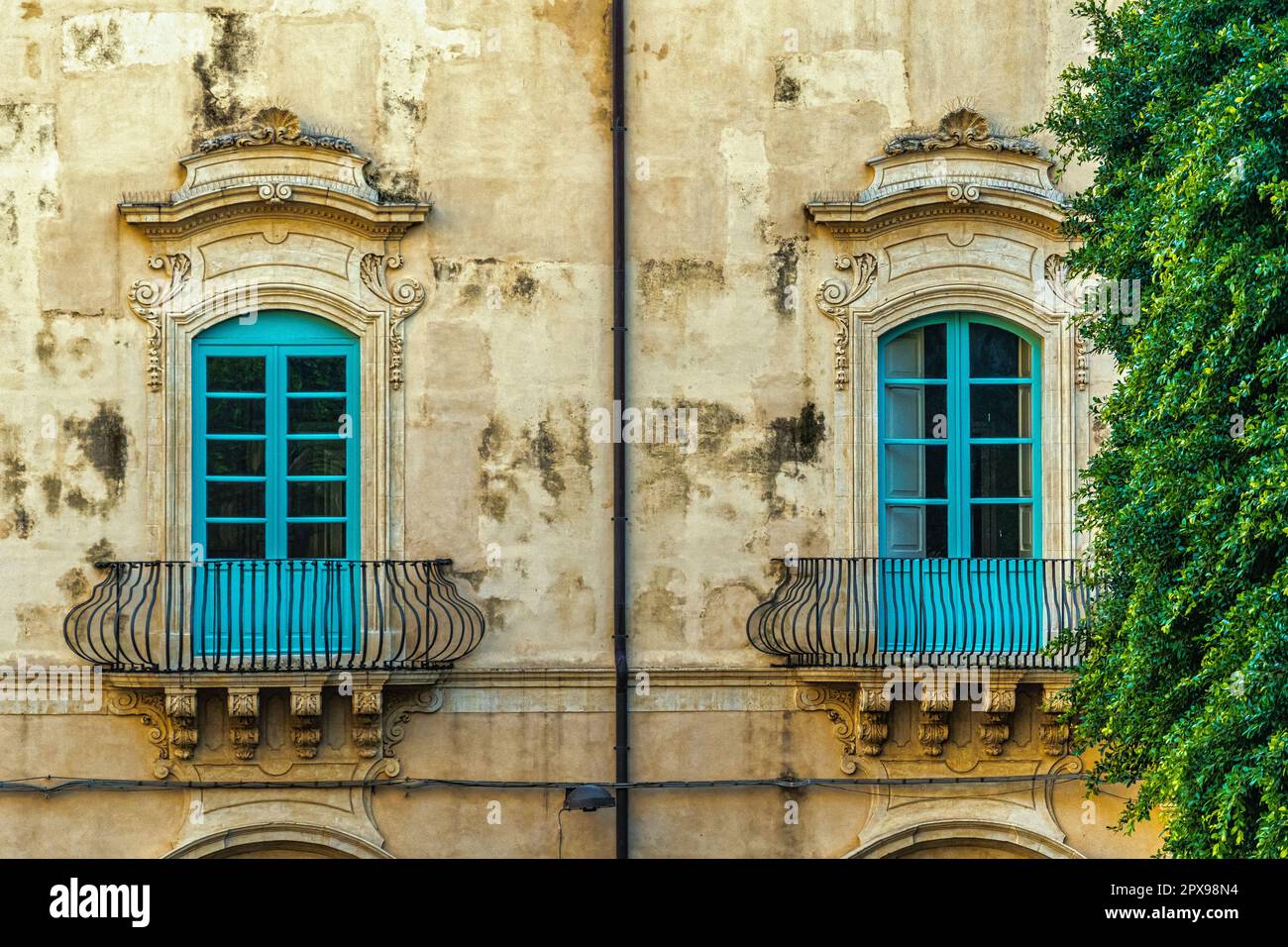 Zwei blaue Fenster mit barocken Dekorationen in einem antiken Gebäude in der Stadt Noto. Noto, Provinz Syrakus, Sizilien, Italien, Europa Stockfoto