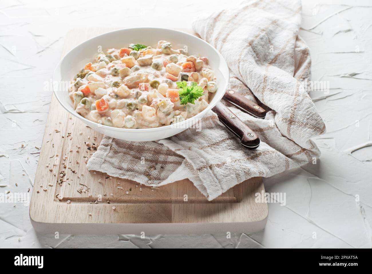 Schale mit russischem Salat oder olivier- oder französischem Salat mit Gemüse und Ei mit Mayonnaise auf einem weißen Tisch Stockfoto