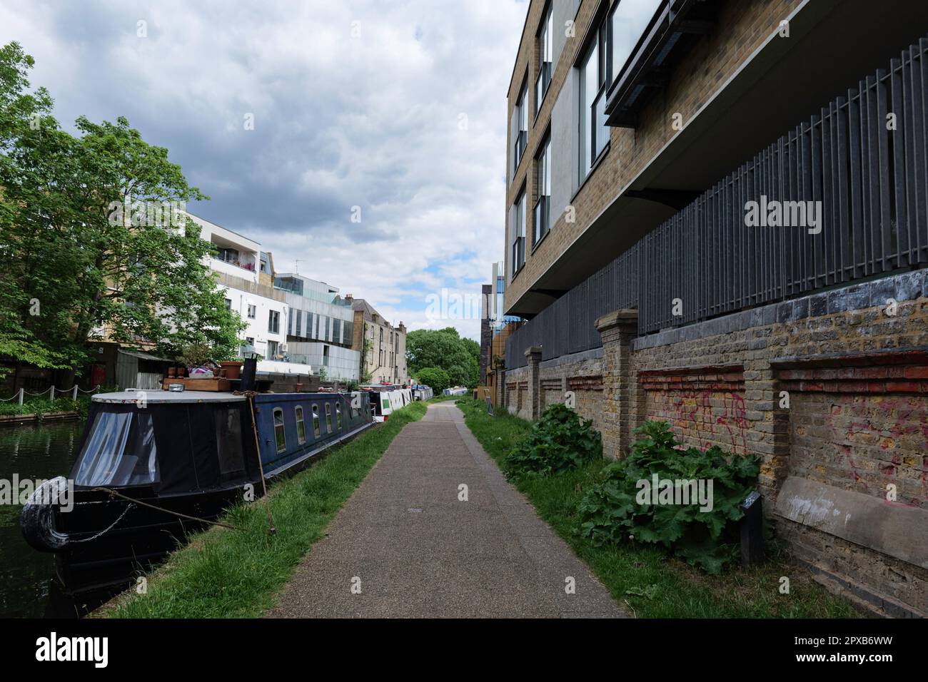 London - 05 21 2022 Uhr: Fußweg entlang des Grand Union Canal in der Nähe der Adela Street mit festgefahrenen Booten Stockfoto