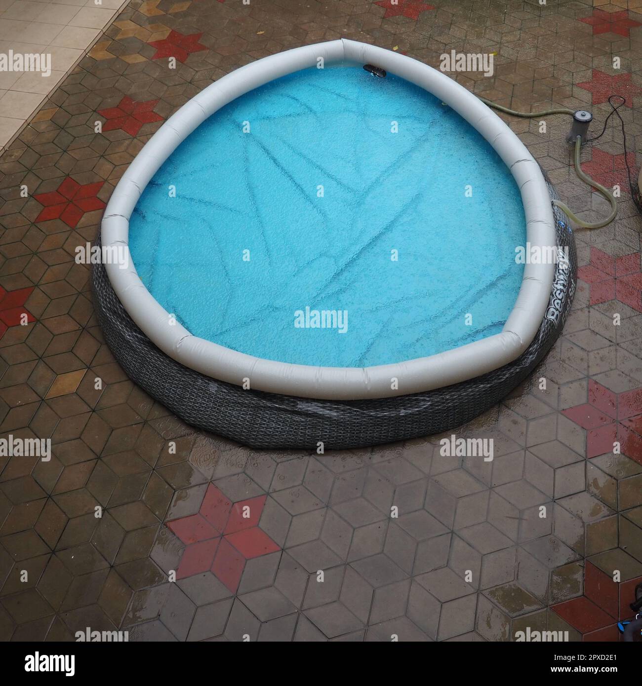 Mit Wasser gefüllter Gummi-Rundpool. Blaues Wasser im Pool. Große Regentropfen fallen auf die Wasseroberfläche. Regnerisches Wetter im Hotel. Niemand Stockfoto