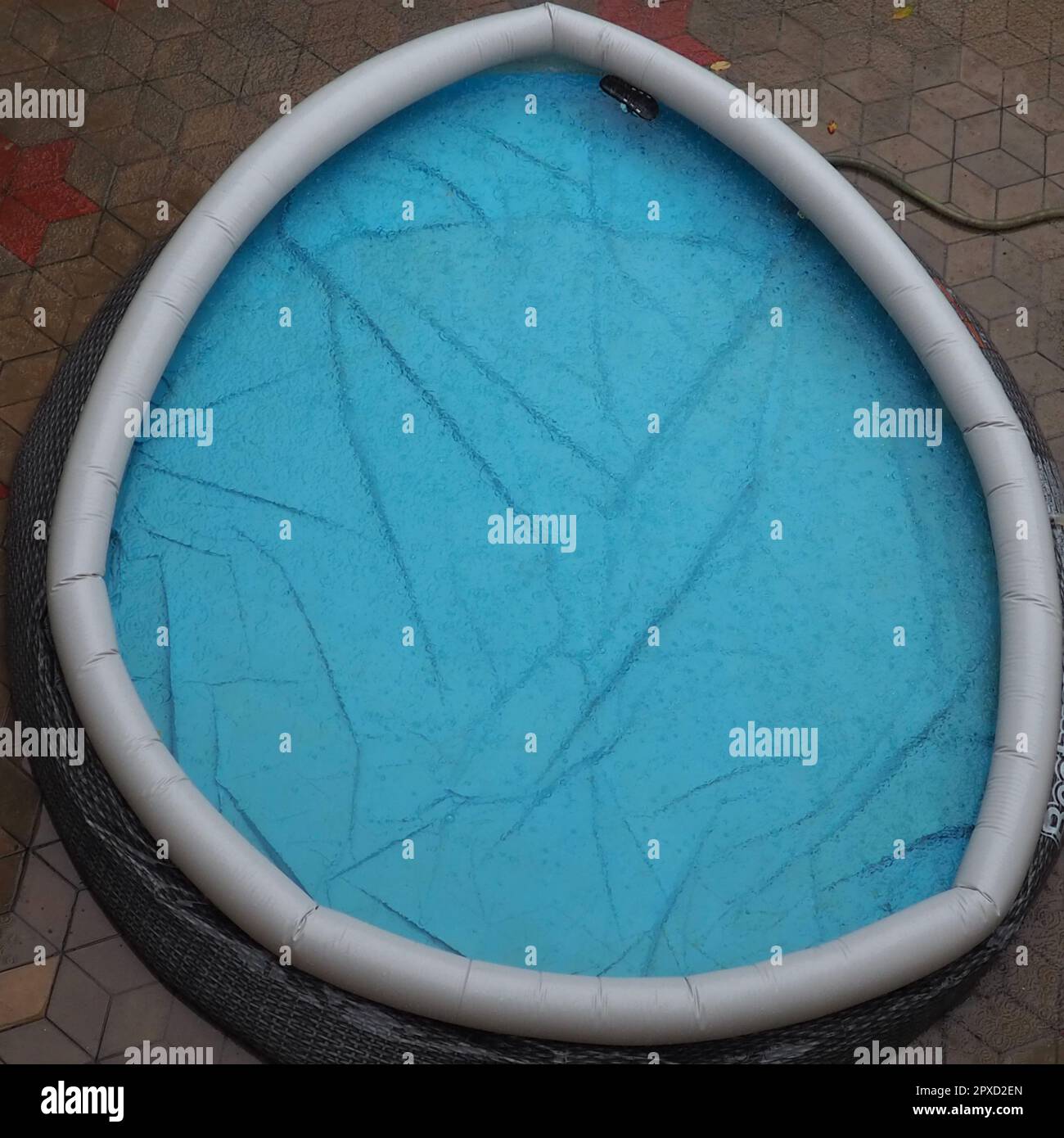 Mit Wasser gefüllter Gummi-Rundpool. Blaues Wasser im Pool. Große Regentropfen fallen auf die Wasseroberfläche. Regnerisches Wetter im Hotel. Niemand Stockfoto
