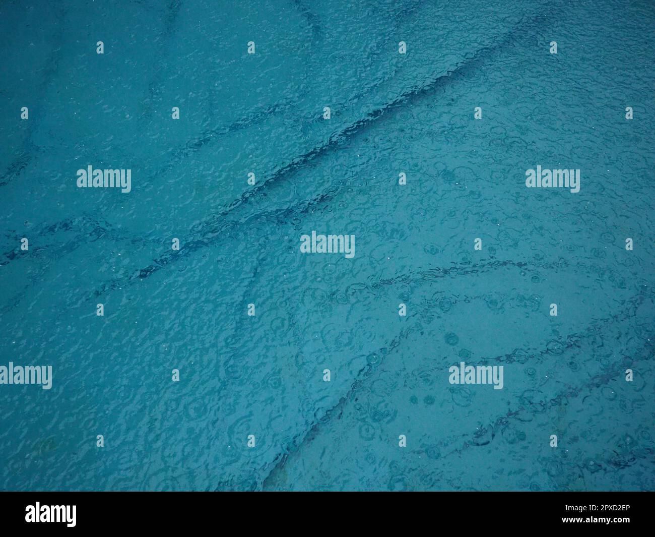 Mit Wasser gefüllter Gummi-Rundpool. Blaues Wasser im Pool. Große Regentropfen fallen auf die Wasseroberfläche. Regnerisches Wetter im Hotel. Niemand Stockfoto