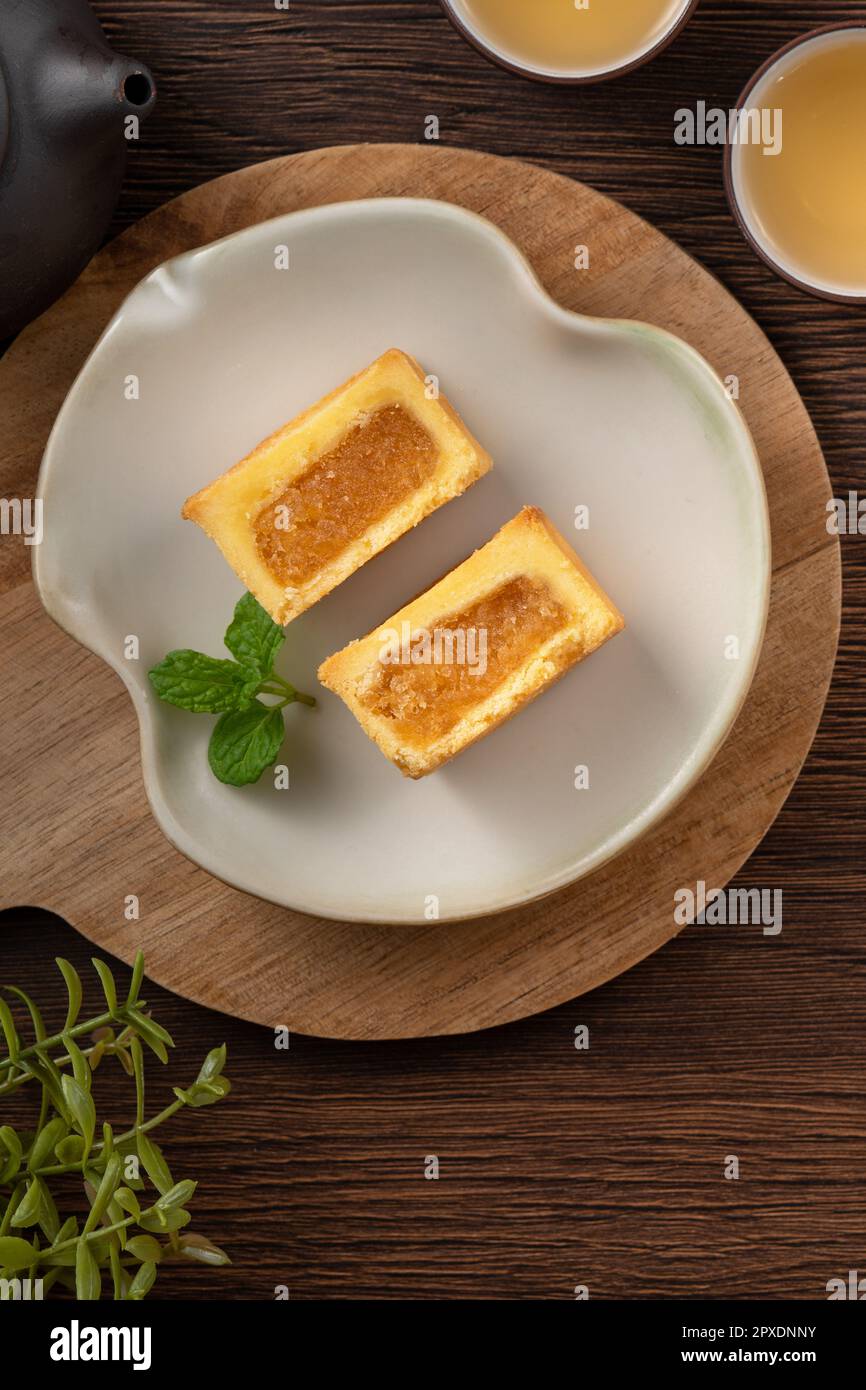 Köstliches taiwanesisches berühmtes Ananaskuchen Gebäck als Dessert auf einem Teller auf einem Holztisch mit heißem Tee. Stockfoto