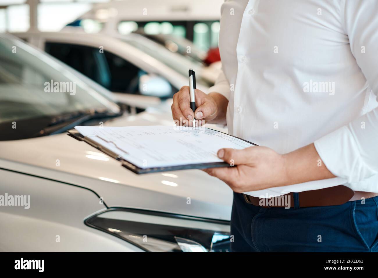 Lesen Sie immer das Kleingedruckte. Ein Autoverkäufer, der auf ein Klemmbrett schreibt. Stockfoto