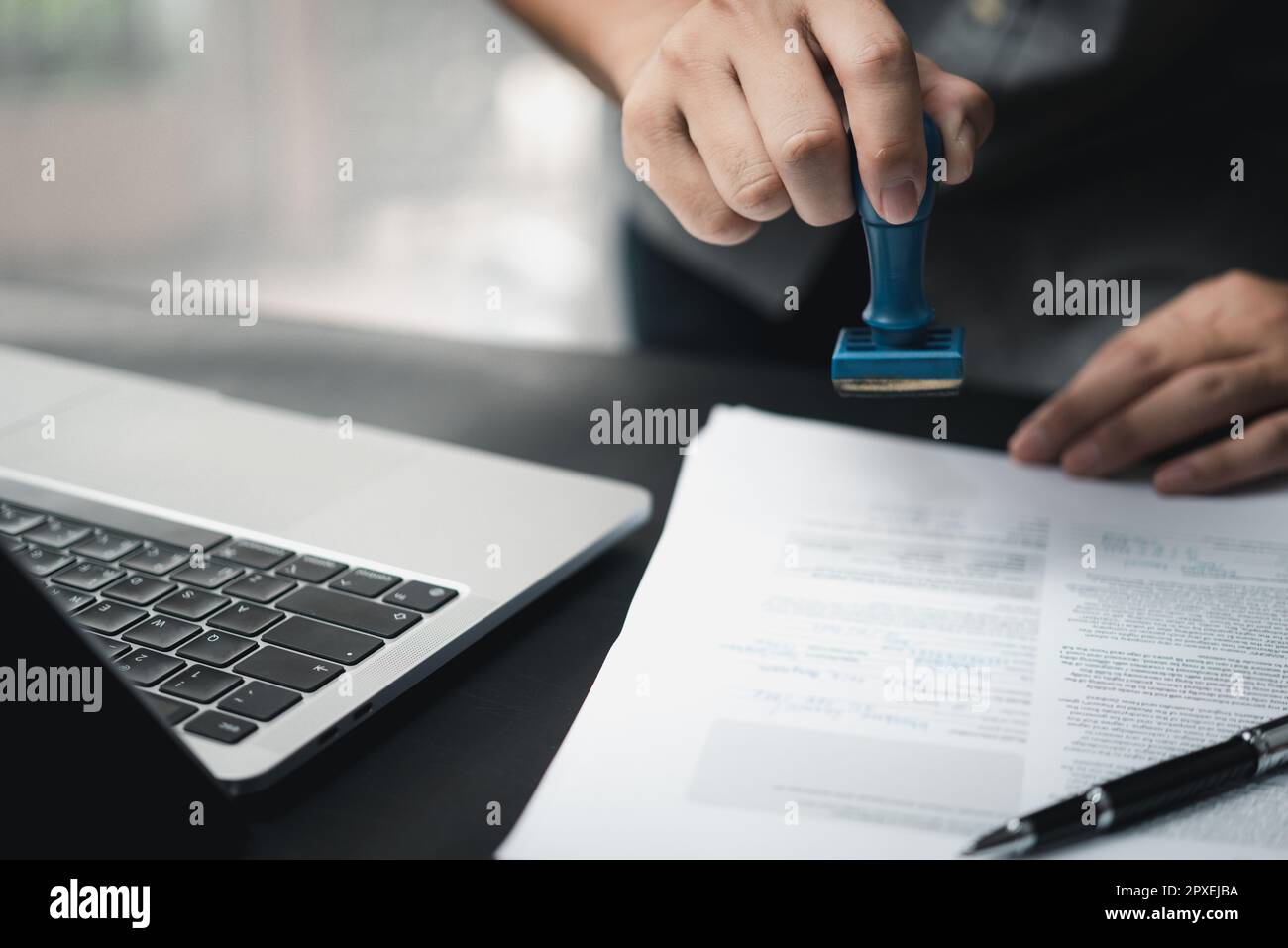 Mann, der die Genehmigung von Dokumenten für das Bankwesen oder das Investment-Marketing auf dem Schreibtisch stempelt. Stockfoto