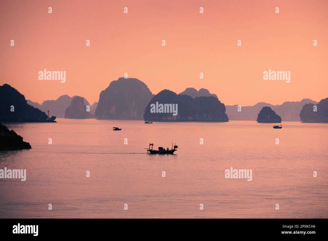 Kleine Boote inmitten von Karstformationen im Meer. Inseln in der berühmten Ha Long Bay in Vietnam. Stockfoto