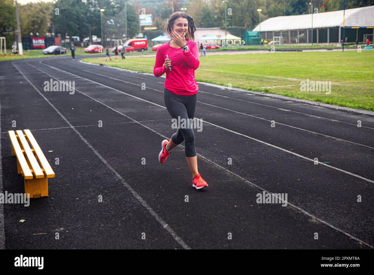 Junge Dame mit Smartphone läuft für Fitness und genießt ein gesundes und elastisches Track Tartan auf dem Spartak Track and Field und Rugby Stad in Kiew, September 2017 Stockfoto