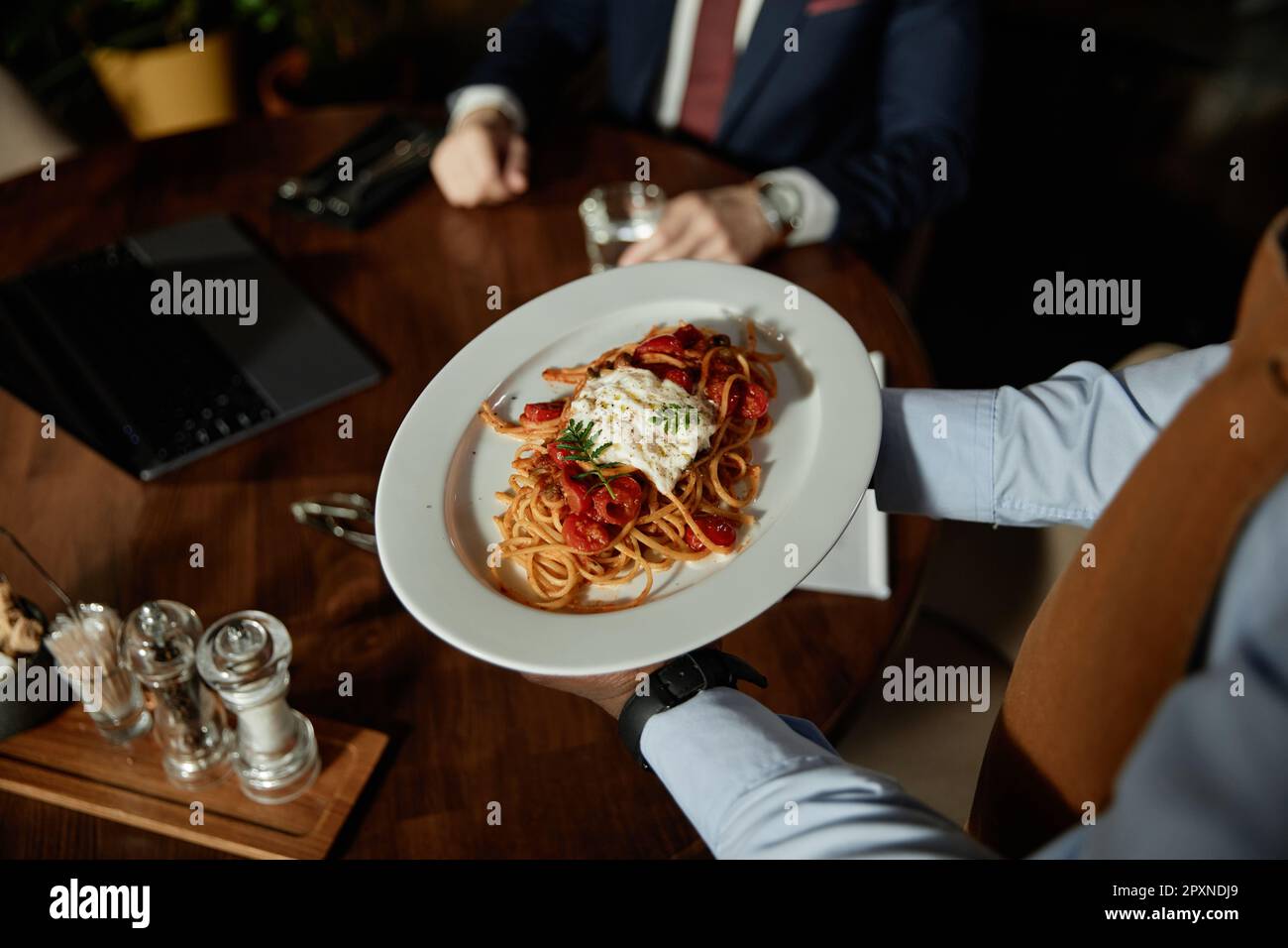 Nahaufnahme des Kellners, der Pasta hält und dem Gast im Restaurant serviert Stockfoto