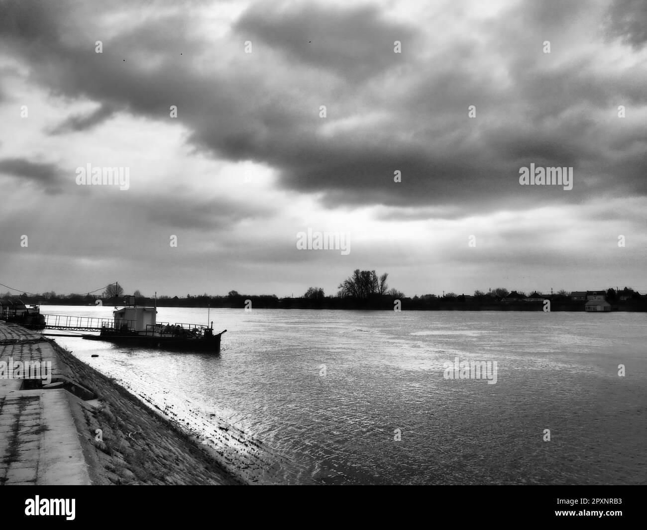 Flusslandschaft mit einem einsamen Schiff vor Anker. Bewölktes Wetter mit schweren Wolken. Reflexion von Wolken im Wasser. Die andere Seite ist der Horizont. S Stockfoto