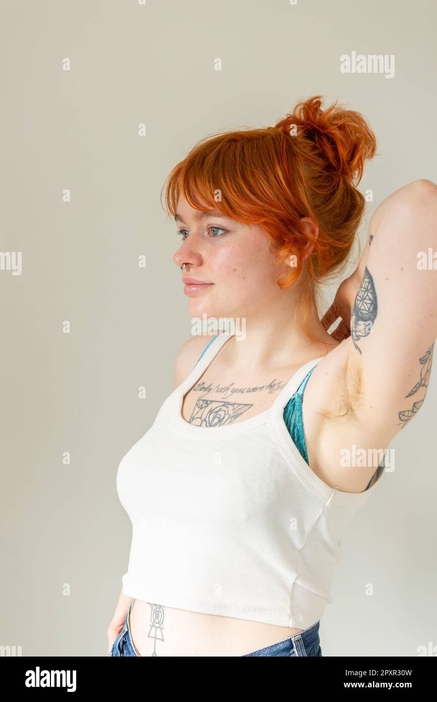 Eine Frau Mitte zwanzig mit gefärbtem Ingwerhaar, Tattoos und Nasenring Stockfoto