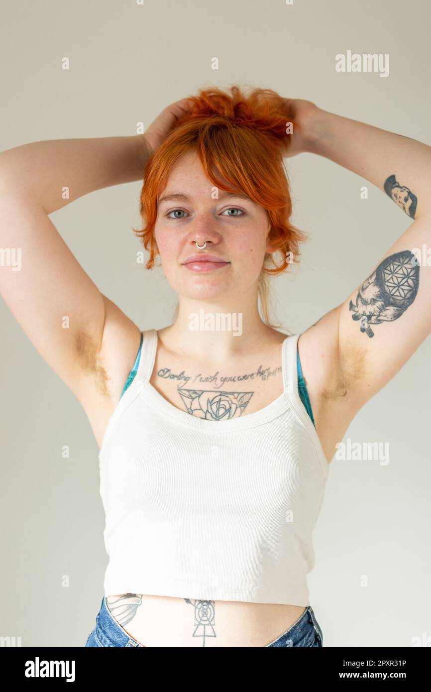 Eine Frau mit Tattoos und haarigen Achseln, mit den Armen hinter dem Kopf Stockfoto