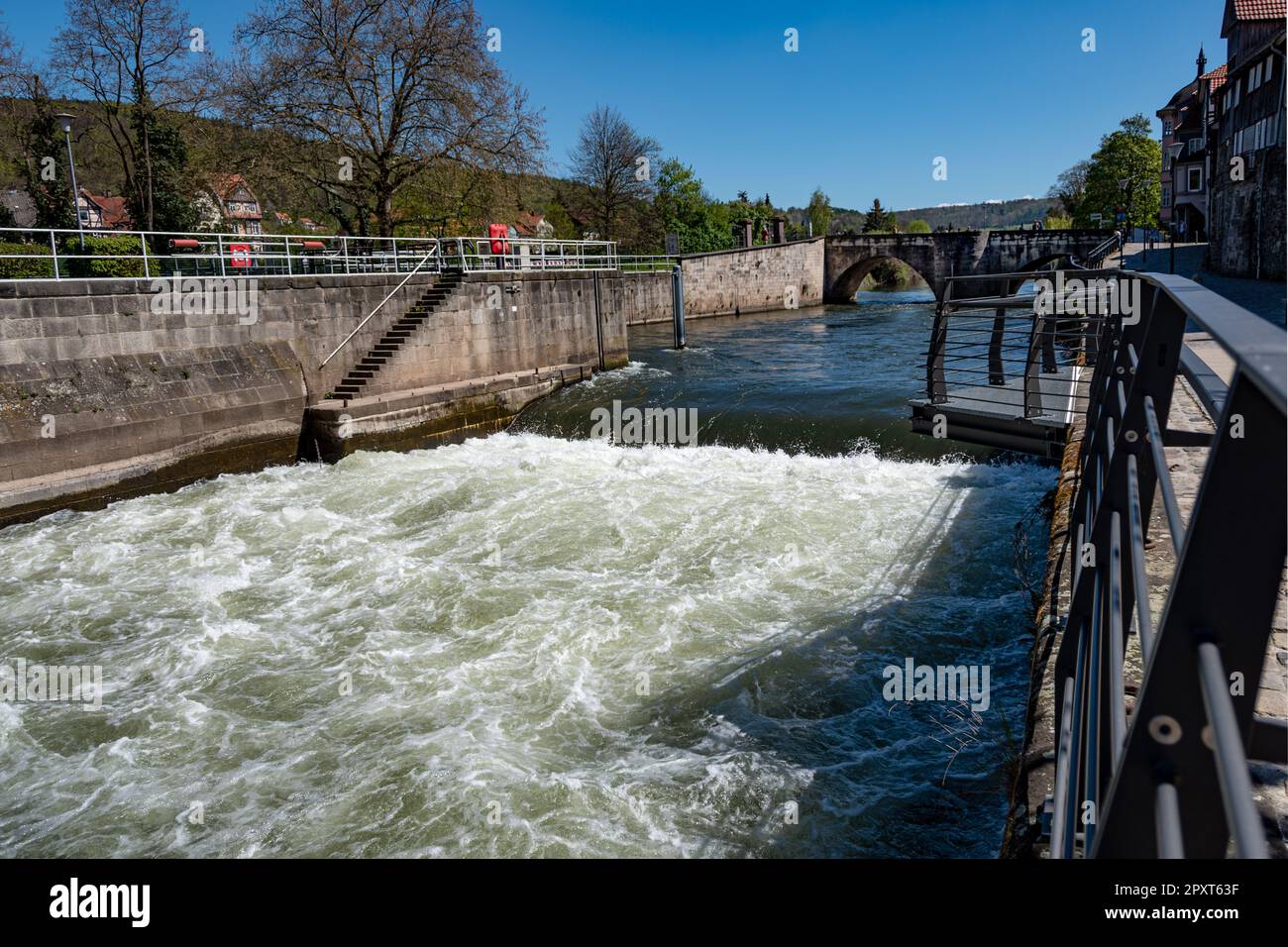 Im Vordergrund ein Wehr, im Hintergrund die alte Werra-Brücke in Hannover Münden. Stockfoto