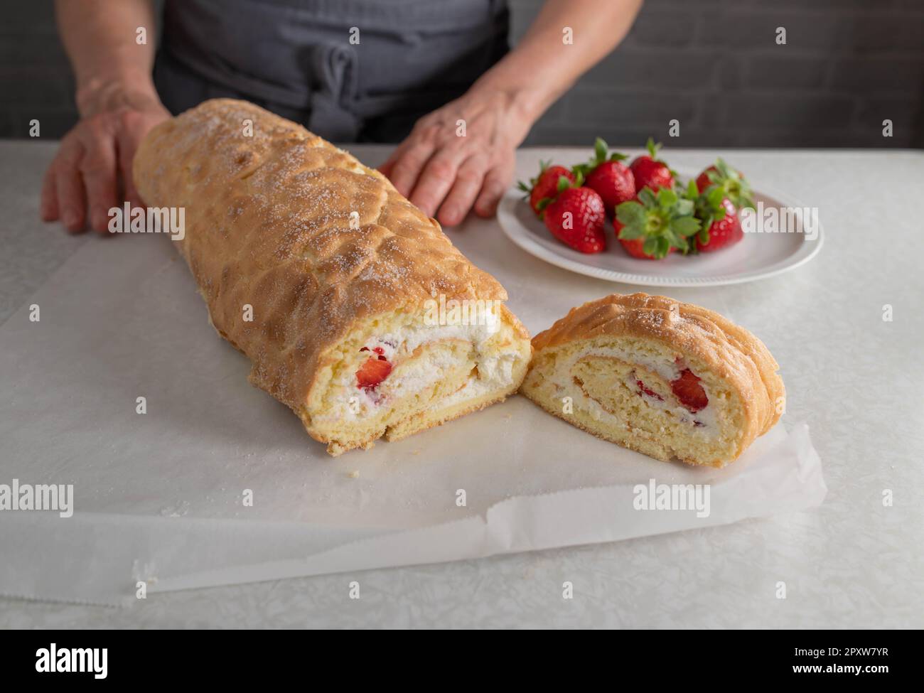 Frisch gebackene und gefüllte schweizer Brötchen mit Schlagsahne und Erdbeerfüllung auf dem Küchentisch ohne Belag Stockfoto