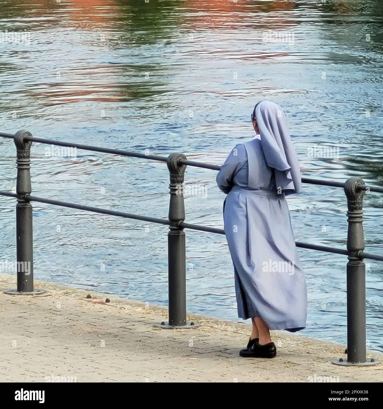 Eine Nonne steht am Fluss und schaut auf das Wasser. Stockfoto